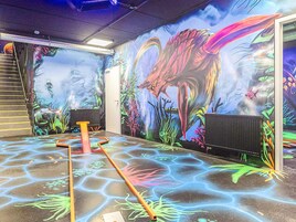 Habitación con un mural de una criatura marina y paisaje submarino, una escalera y un radiador.