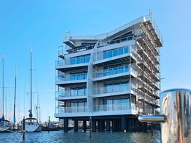 A multi-story building with a modern architectural design, featuring balconies and large windows.
