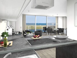A modern kitchen with a large island, dining area, and a view of the sea.