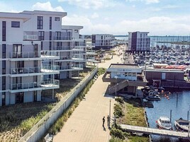 Et kystnært boligområde med moderne bygninger, en lysthavn og en sti for fodgængere.