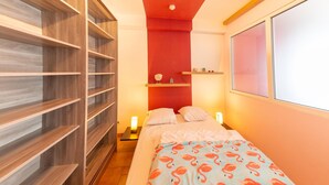 Un dormitorio con cama, armario, mesita de noche y estante en la pared.