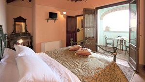 A bedroom with a bed, a dresser, a mirror, a television, and a balcony with chairs. - Belvilla by OYO Ciliegi (Cortona)