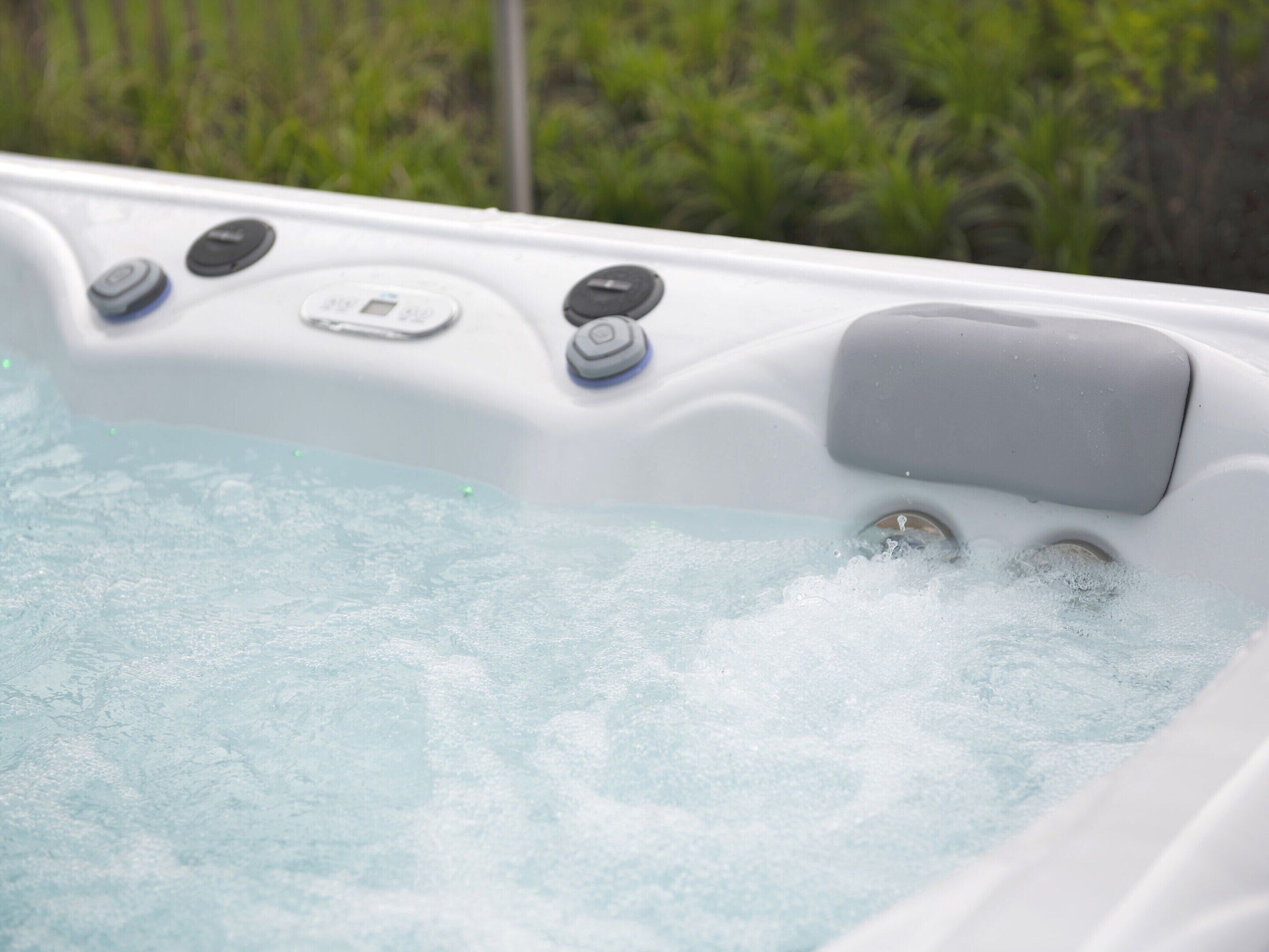 Ein Whirlpool mit Bedienelementen und einem digitalen Display, umgeben von Grünpflanzen.