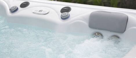 Ein Whirlpool mit Bedienelementen und einem digitalen Display, umgeben von Grünpflanzen.