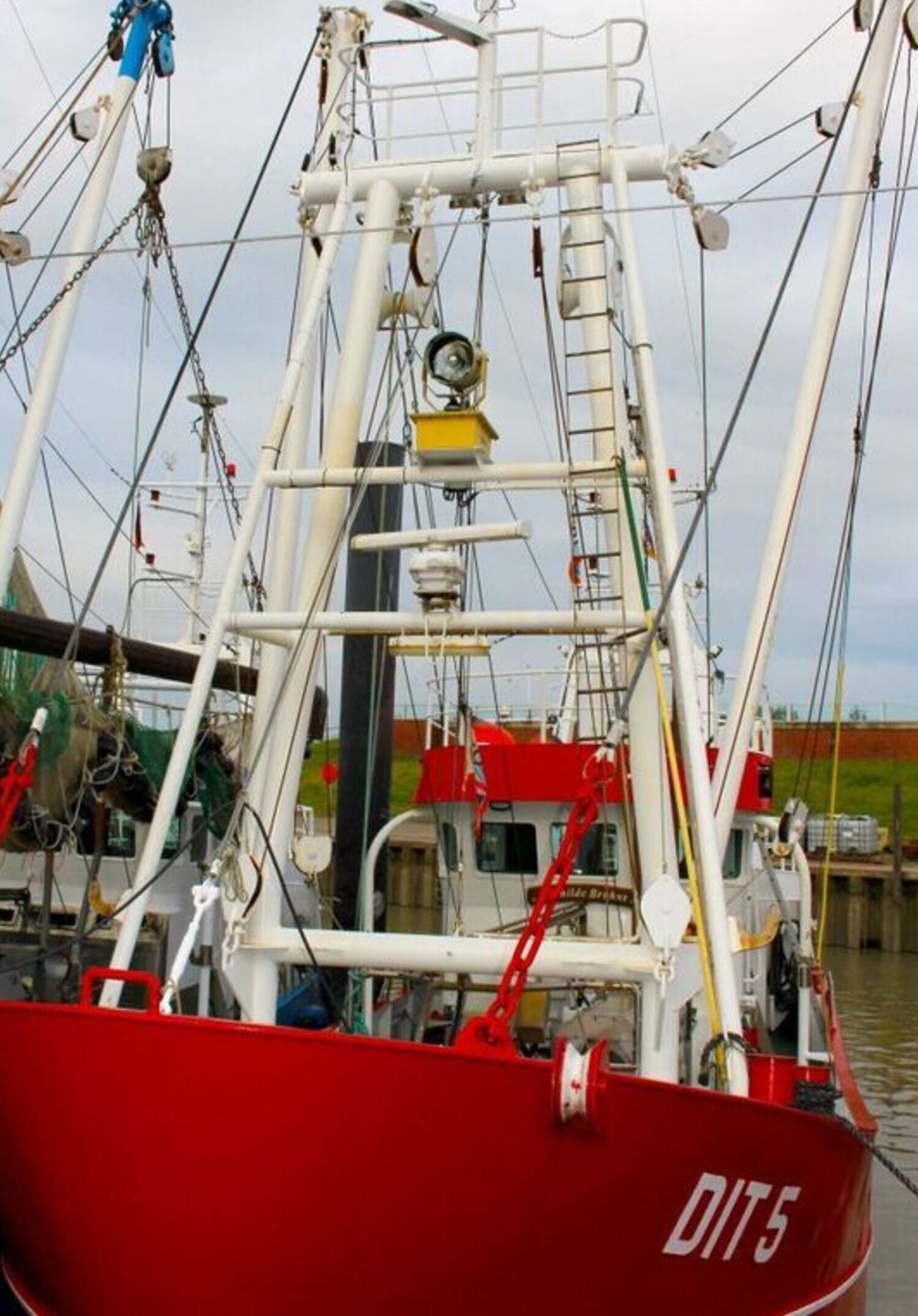 Ein rotes Fischerboot liegt an einem Steg, mit sichtbarer Ausrüstung und einer Leiter.