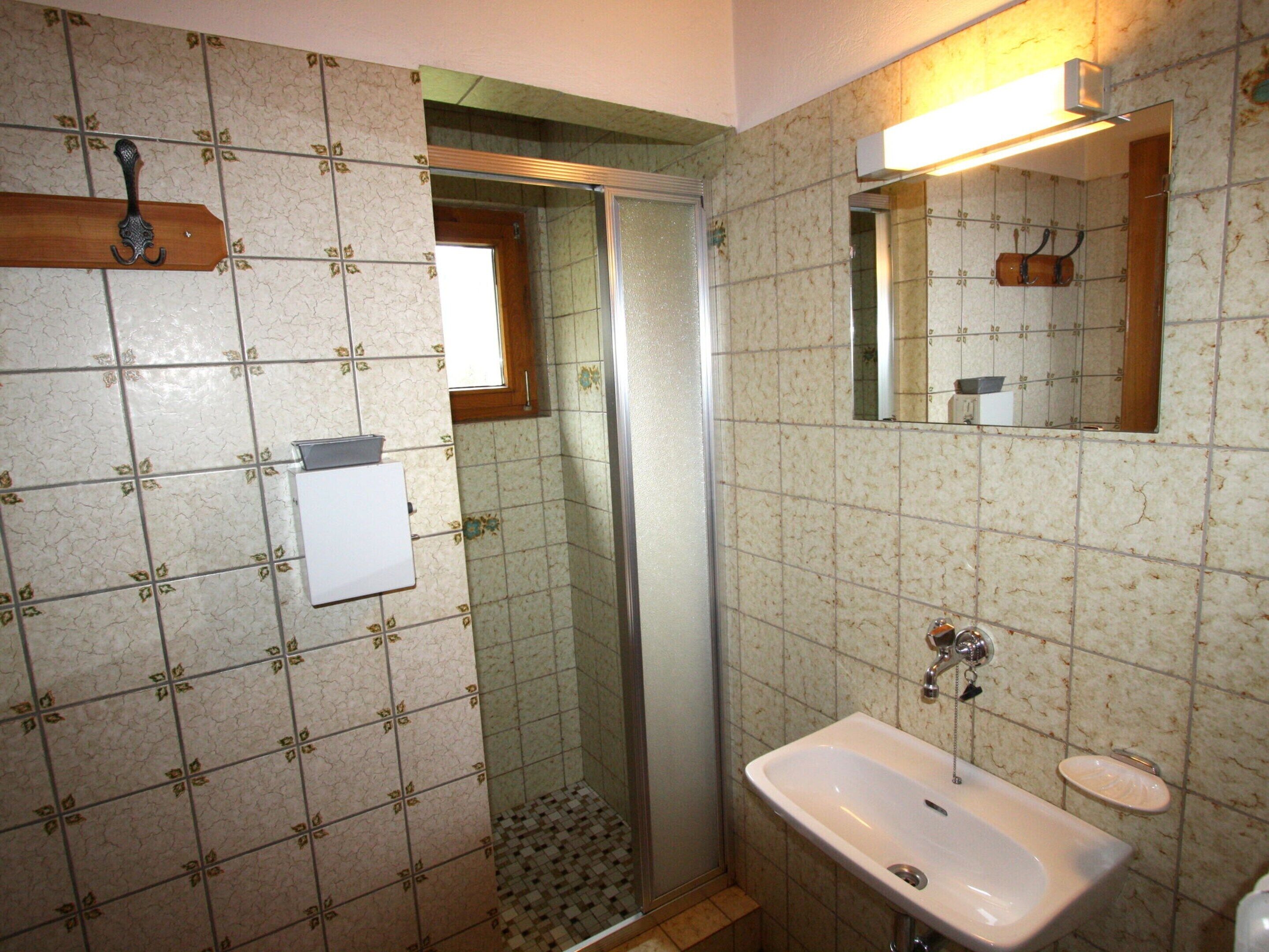 A bathroom with a shower, a sink, and a mirror.