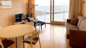 Une chambre d’hôtel avec un balcon, une table à manger, un téléviseur, un canapé et une chaise.