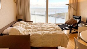 Une chambre d’hôtel avec un grand lit, un bureau, une chaise et une vue sur la mer.