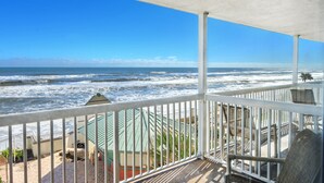 A balcony with a view of the ocean, white railings, and a covered area with chairs. - Oceanfront Balcony | 1BR  | Pools |Hot Tubs (Daytona Beach)