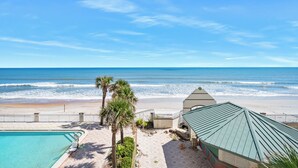 A beachfront property with a swimming pool, palm trees, and a beach view. - Oceanfront Balcony | 1BR  | Pools |Hot Tubs (Daytona Beach)
