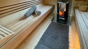 Un sauna avec des bancs en bois et une cheminée en pierre.