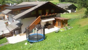 Un chalet doté d’un balcon, d’un trampoline et offrant une vue sur les montagnes.