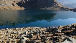 Un lac de montagne aux rives rocheuses et aux eaux cristallines où se reflètent les paysages.