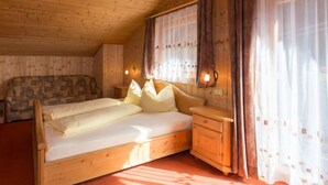 Une chambre dans une cabane en bois, avec un lit, une chaise et une table de chevet.