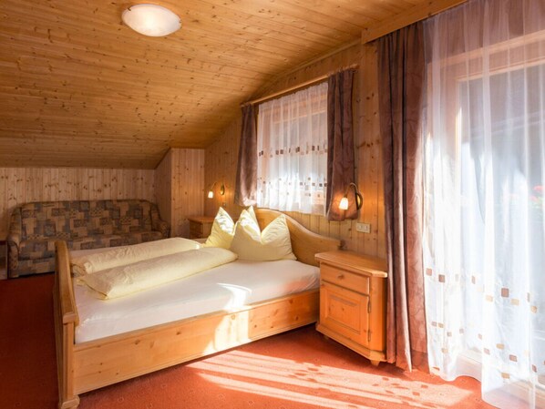 A wooden cabin bedroom with a bed, a chair, and a nightstand.