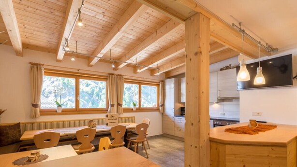 Un intérieur en bois comprenant un coin repas, une cuisine et de grandes fenêtres.