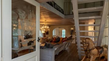Een ruime kamer met een houten trap, een kroonluchter en een houten schommelpaard.