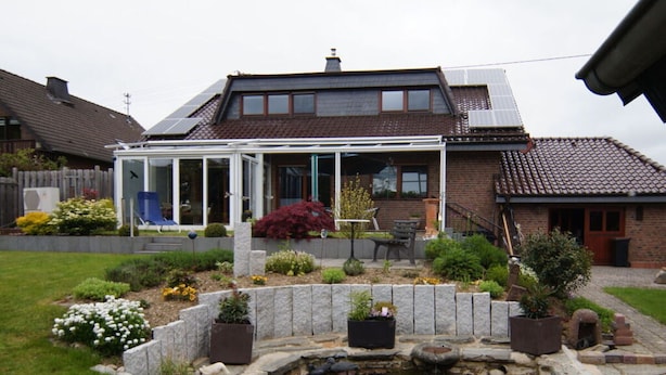 A house with a conservatory, a garden with a pond, and a brick exterior. - Liefde Voor de Eifel (Huertgenwald)