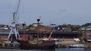 Un grand navire était amarré dans un port, avec une grue et des bâtiments en arrière-plan.
