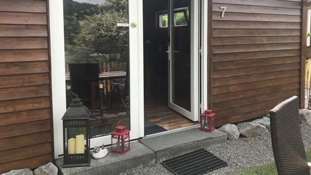 Ett trähus med en skjutdörr av glas, husnummer 7, och två lyktor utanför.