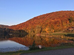 A serene lakeside view with a cabin on a hillside. - Holiday Home Lower Lake Terrace (Rieden)