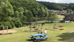 En park med picknickbord, gungor och en lekplats.