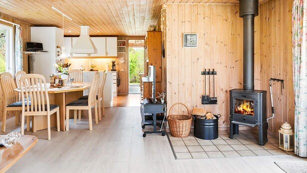 Un interior de cabaña acogedor con comedor, cocina y estufa de leña.