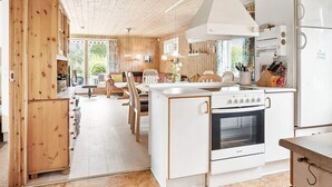 Una cocina moderna con electrodomésticos blancos, armarios de madera y una isla central.