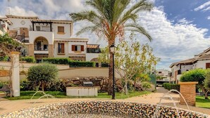 A residential area with a mosaic fountain, a palm tree, and a building with balconies. - Apartment in Spain Near Sandy Beach (Vera)
