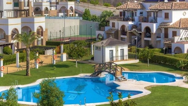 A residential area with a swimming pool, a small bridge, and a white building with a balcony. - Apartment in Spain Near Sandy Beach (Vera)