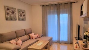 A living room with a sofa, a coffee table, a TV, and a window with curtains. - Apartment in Spain Near Sandy Beach (Vera)