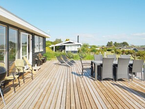 A wooden deck with outdoor furniture, including chairs and a table, overlooking a residential area.