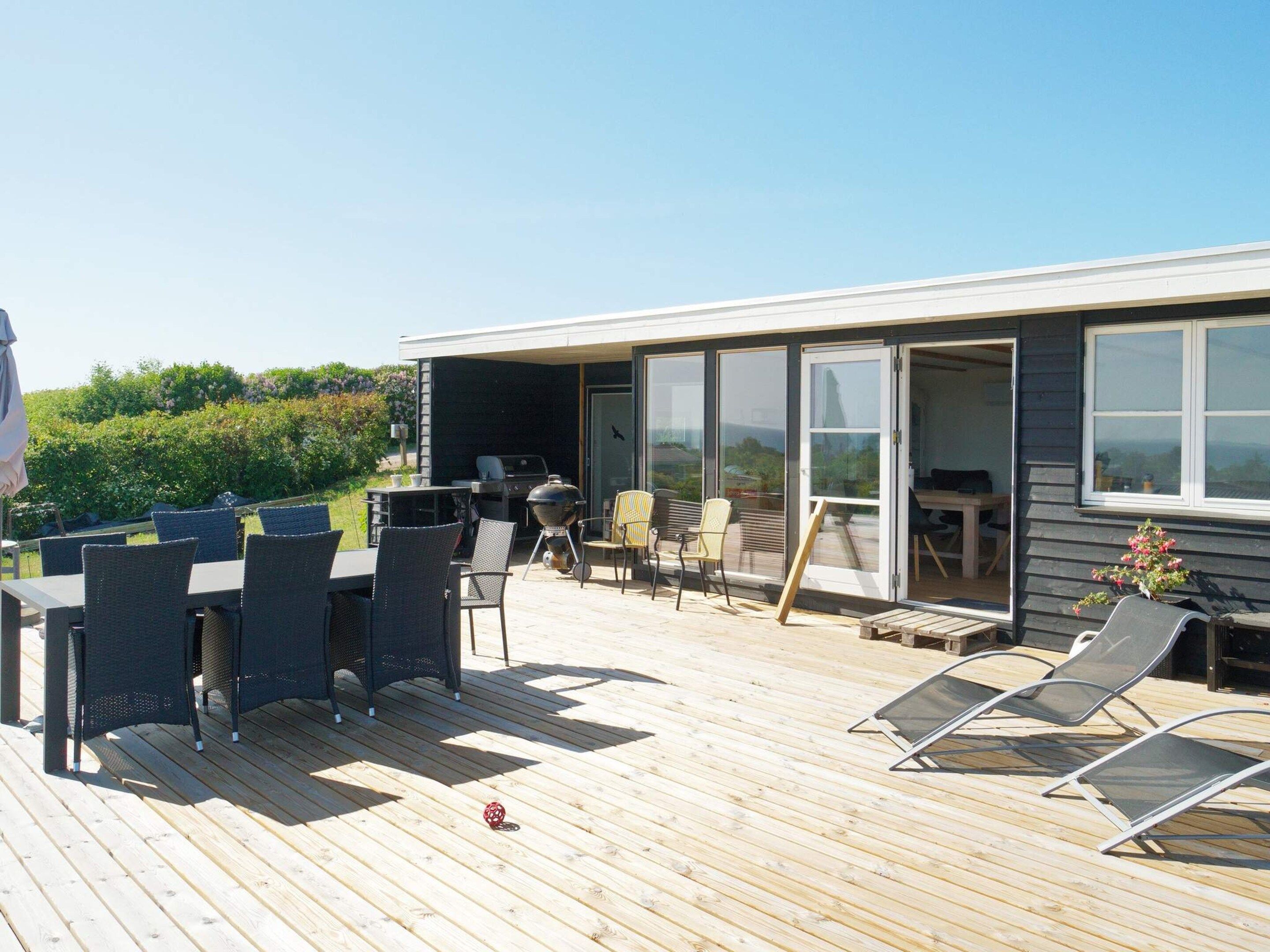 Una terrazza esterna con zona pranzo, sedie e barbecue.