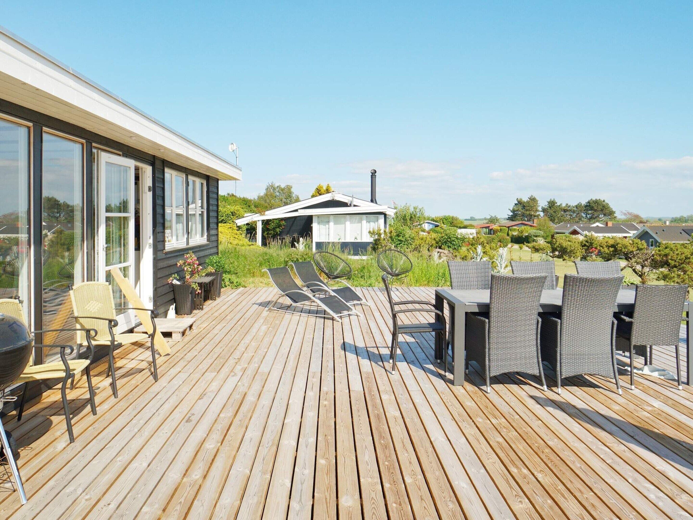 A wooden deck with outdoor furniture, including chairs and a table, overlooking a residential area.