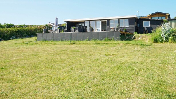 A modern house with a large open patio area, a fenced yard, and a clear sky. - 4 Person Holiday Home in Slagelse (Slagelse)