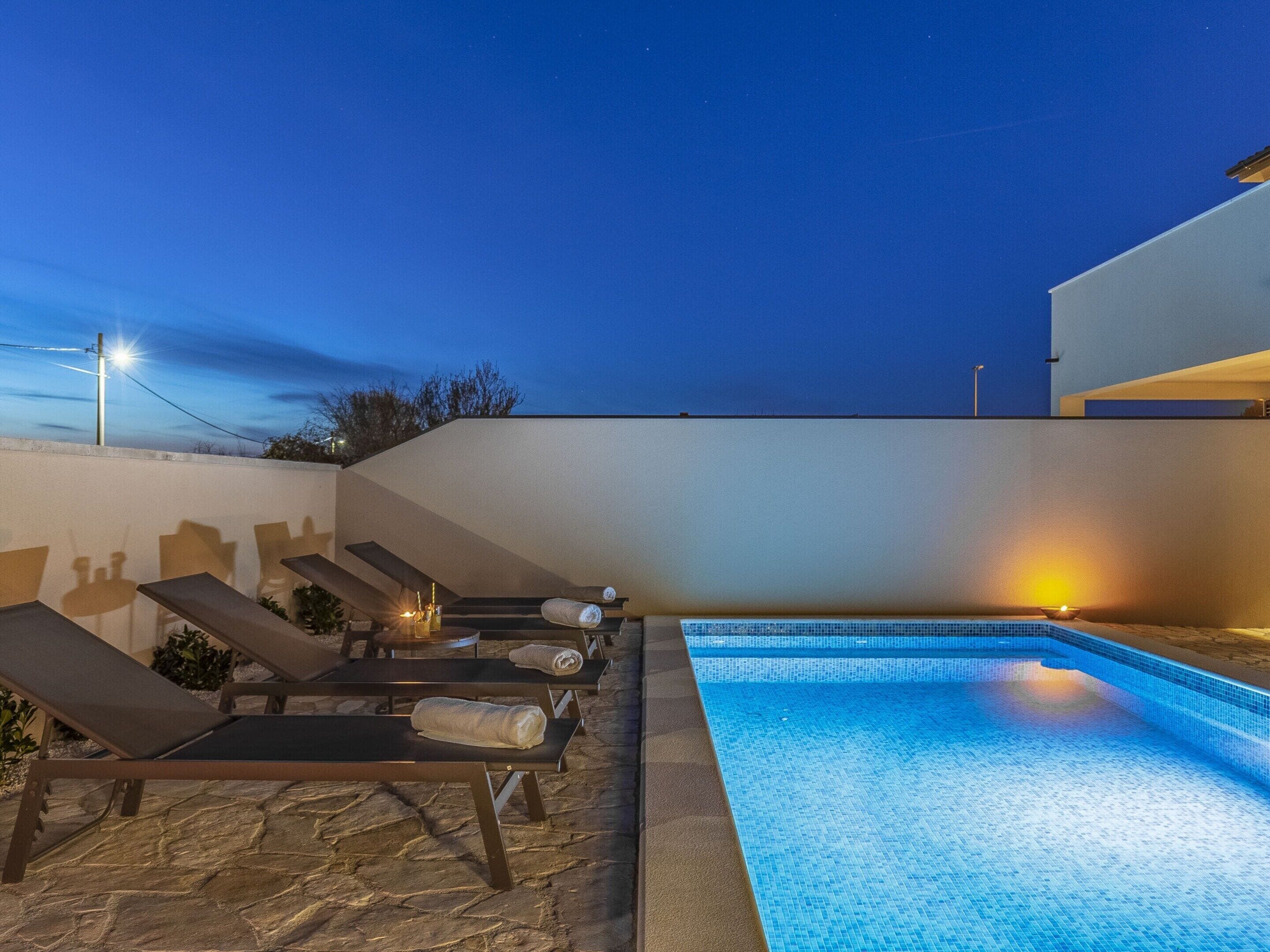 An outdoor swimming pool area with lounge chairs and a stone floor.