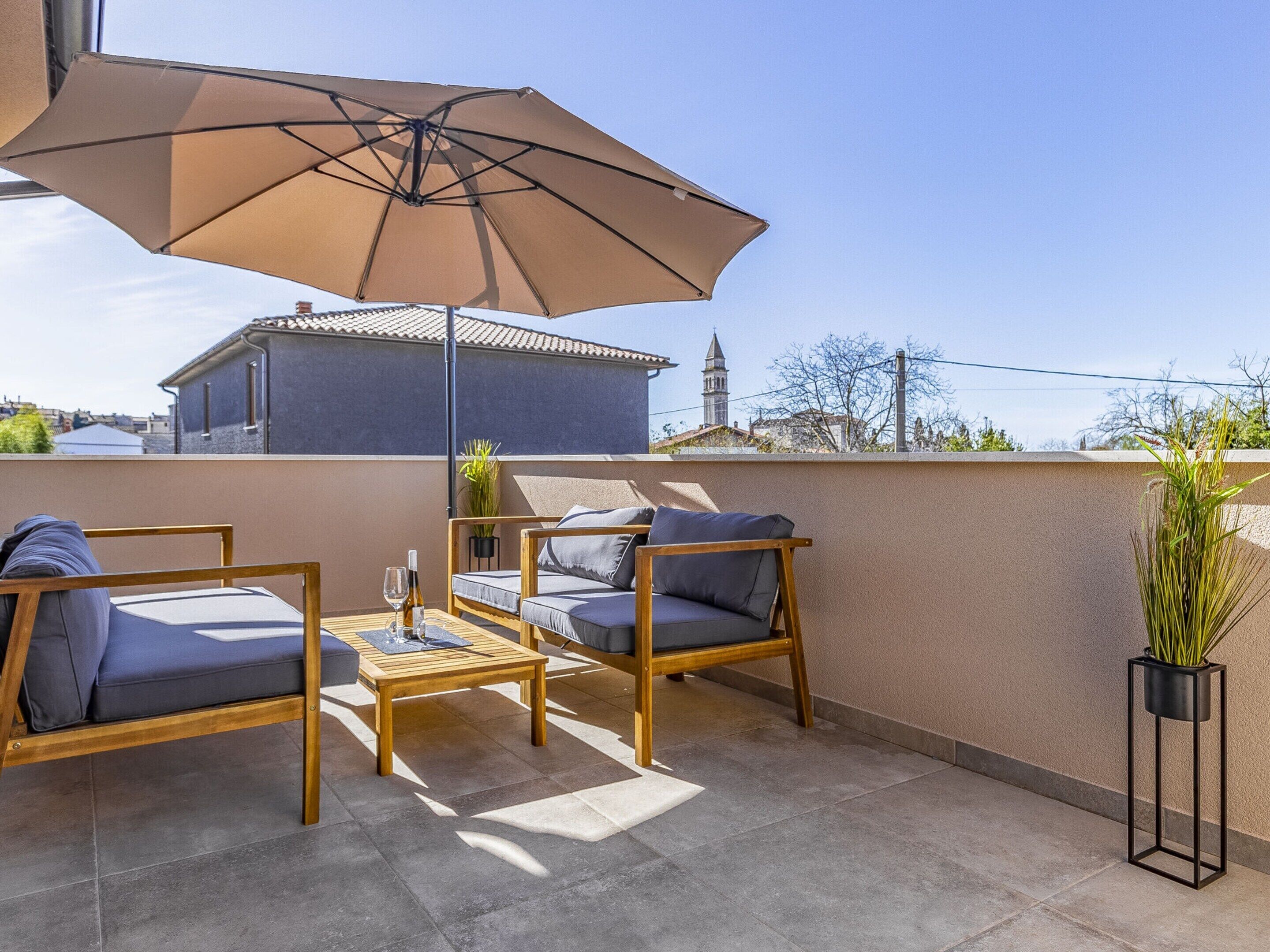 A patio with two wooden chairs, a table, and a large umbrella.