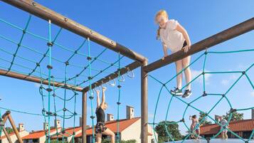Un parque infantil con una estructura de red y vigas de madera.