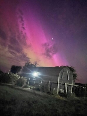 A house with a porch and a fence in front, under a night sky with a pinkish hue.