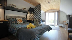 Une chambre à coucher avec un lit, un bureau, une chaise et une grande fenêtre.