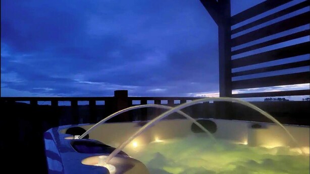 Un bain à remous avec une terrasse en bois et une vue sur le ciel.