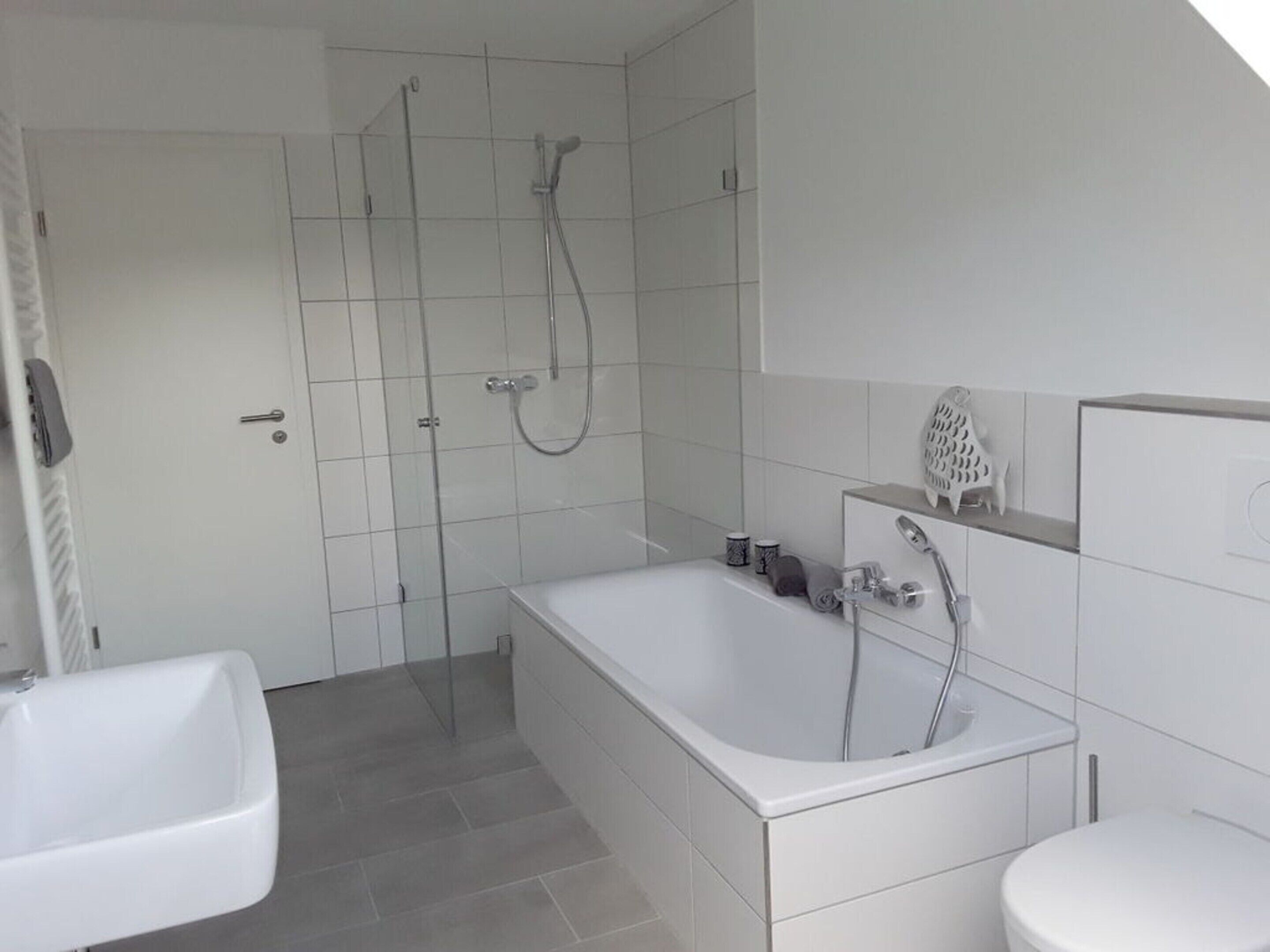 A modern bathroom with a bathtub, a shower, and a sink.