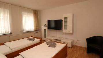 A hotel room with two beds, a TV, a small cabinet, and a chair.