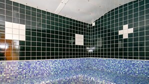 A tiled pool area with a blue mosaic border and a white ceiling.
