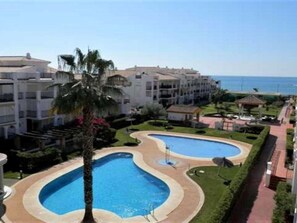 Relax by the kidney-shaped pools surrounded by lush gardens and palm trees, offering a serene coastal retreat.