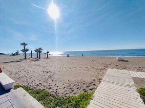 A beach with a wooden walkway leading to the water, palm trees, and a clear sky. - Cozy Apartment in Torrox With Shared Pool (Torrox)