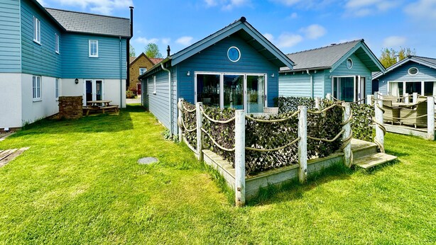 A row of blue cottages with a grassy yard and a wooden fence. - Stunning Coastal Beach House - Sleeping 4 in 2 Bedrooms - Pool and Beach Access Included. (Filey)