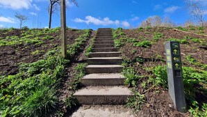 A set of stone steps leading up a hill, surrounded by greenery and a clear blue sky. - Holiday Home in Scherpenisse Near the Sea (Scherpenisse)