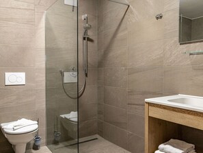 A modern bathroom with a glass-enclosed shower, a toilet, and a sink with a wooden vanity. - Apartment in Schruns Near Silvretta Ski Area (Schruns)