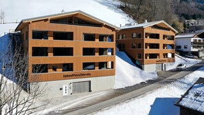 A multi-story building with a wooden facade, labeled 'UplandParcSillfretta,' featuring balconies and a ski slope. - Apartment in Schruns Near Silvretta Ski Area (Schruns)
